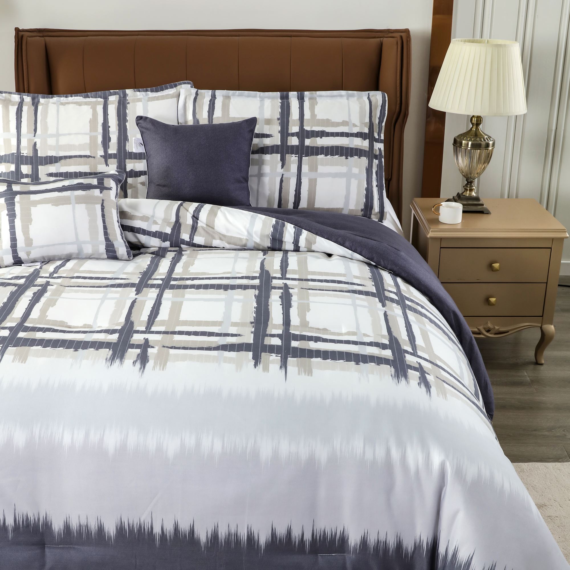 Five-piece comforter set in grey and white checks with navy accent pillow, dressed on an upholstered bed